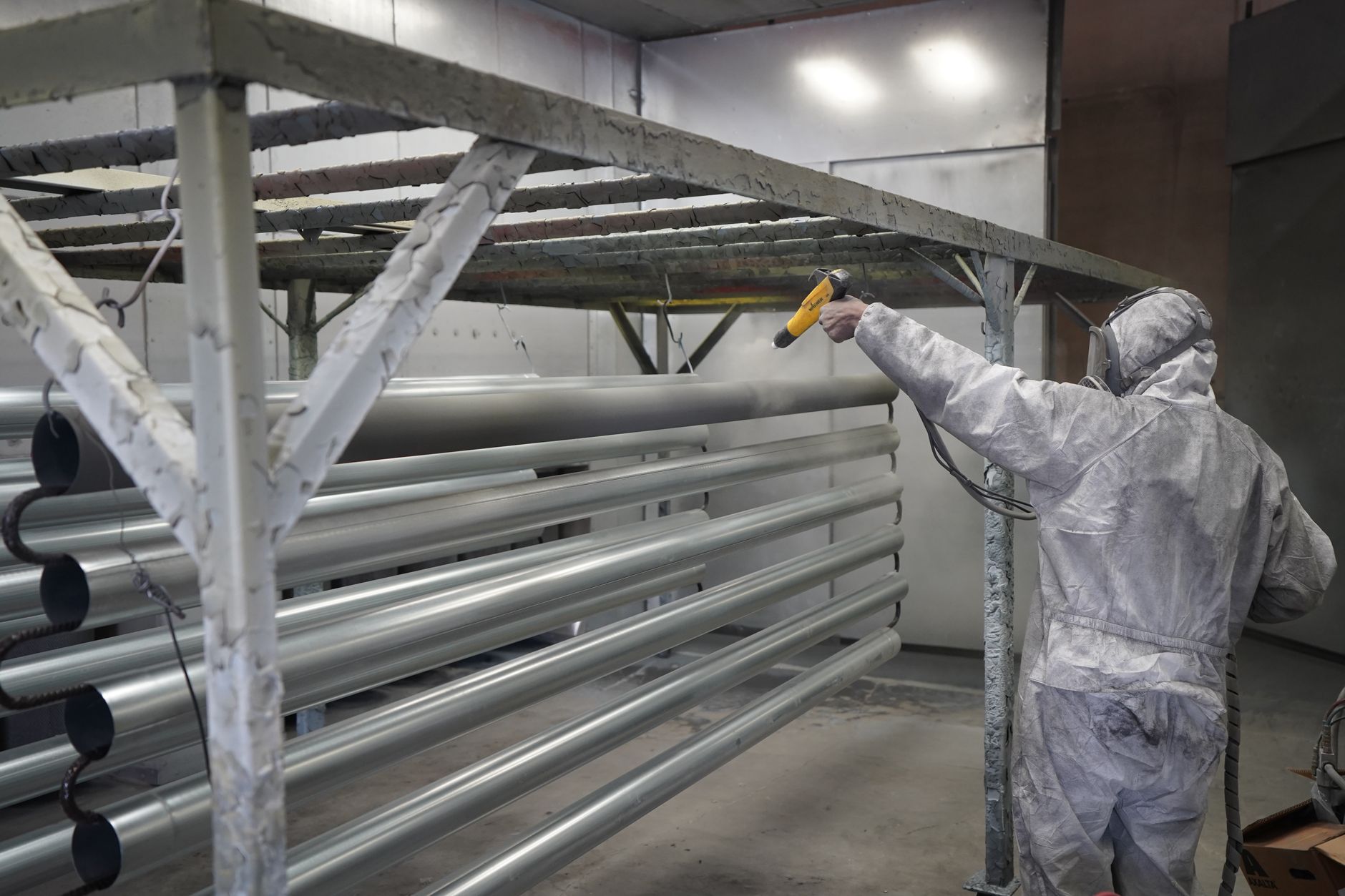 Technician applying powder coating to metal pipes in a workshop setting in Allen, TX